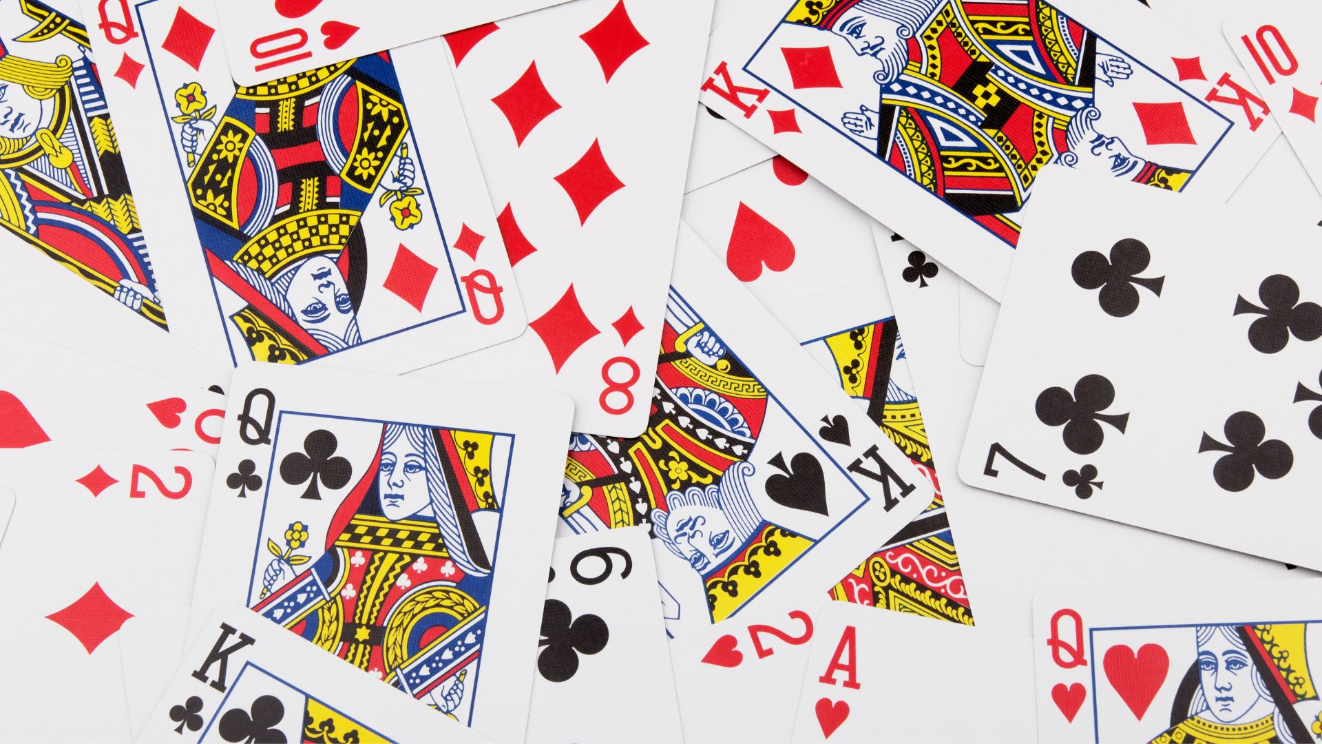 A scattered pile of playing cards featuring various suits and face cards, including kings, queens, eights, and sevens, overlapping each other on a white background.